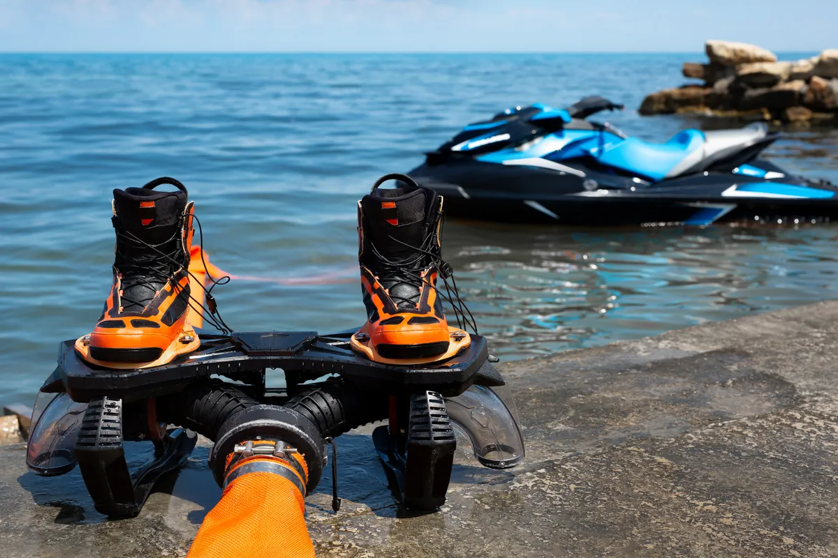 Orange wakeboarding boots and a personal watercraft near the shoreline, illustrating recreational watercraft activities